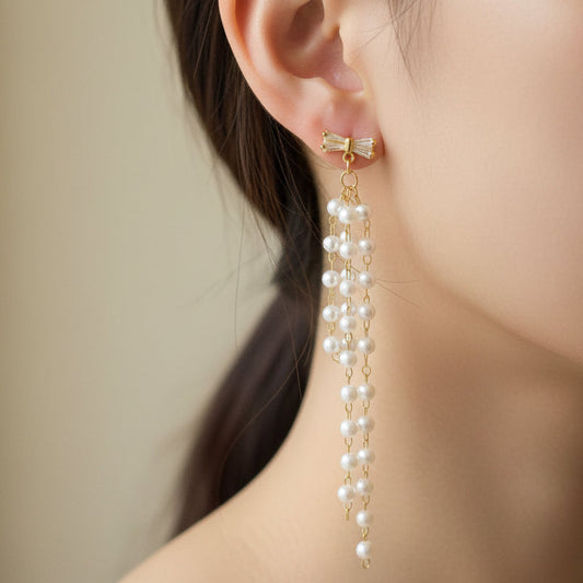 Pearl earrings on a clear hanger against a black background